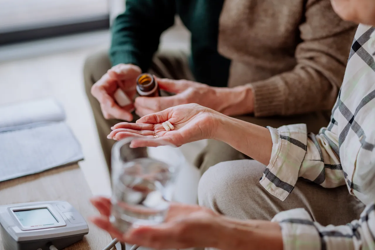 Person taking daily prescription pills with a glass of water